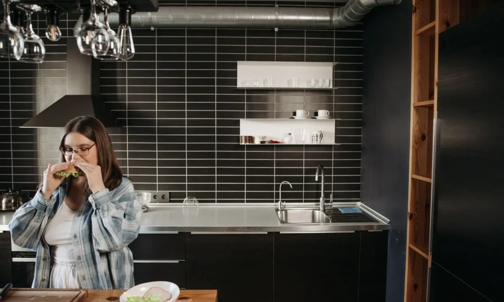 Mujer comiendo en la cocina